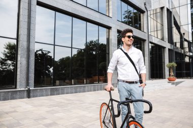 Beyaz gömlek, açık havada bisiklet ile yürüyüş yakışıklı genç iş adamı giyinmiş