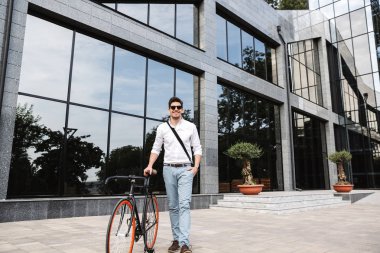 Beyaz gömlek, açık havada bisiklet ile yürüyüş yakışıklı genç iş adamı giyinmiş