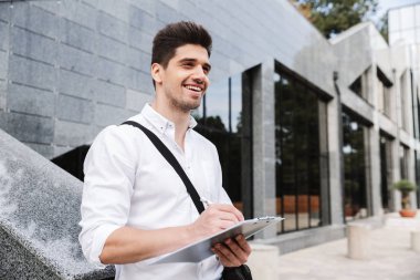 Kendine güvenen başarılı genç işadamı beyaz gömlek açık havada, çalışan giyinmiş tablet holding, belirterek
