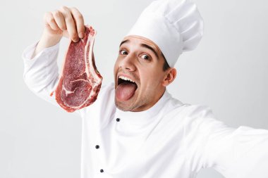 Bir selfie alarak giyen üniforma gösteren ham sığır eti biftek beyaz arka plan üzerinde izole neşeli Şef aşçı