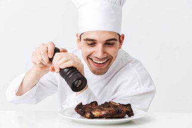 Neşeli şef yemek giyen üniforma biber sığır eti biftek beyaz arka plan üzerinde izole bir plaka üzerinde pişmiş