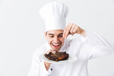 Neşeli şef yemek giyen üniforma biber sığır eti biftek beyaz arka plan üzerinde izole bir plaka üzerinde pişmiş