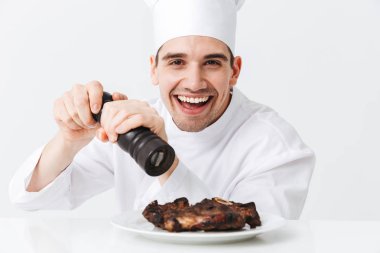 Neşeli şef yemek giyen üniforma biber sığır eti biftek beyaz arka plan üzerinde izole bir plaka üzerinde pişmiş