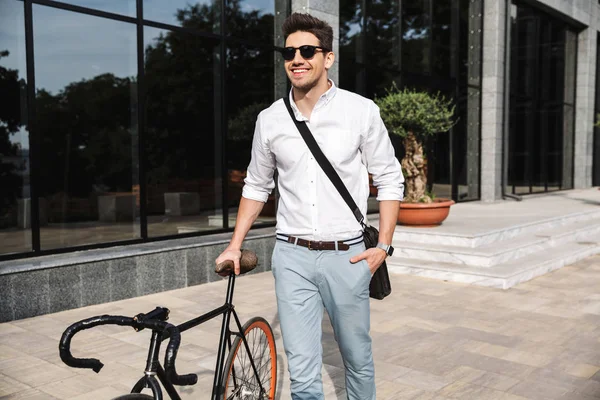 ハンサムな若いビジネスマンは自転車で野外を歩いている白いシャツを着てください — ストック写真