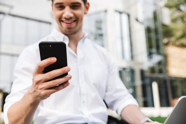 Закрыть Счастливого Молодого Бизнесмена Пользующегося Мобильным Телефоном Сидя Улице Ноутбуком — стоковое фото