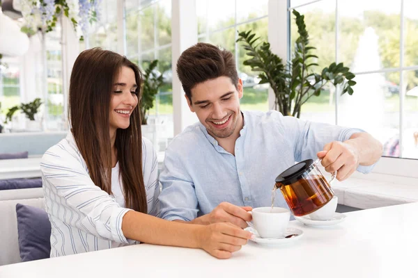 お茶を飲んで カフェのテーブルに座って幸せな若いカップル — ストック写真