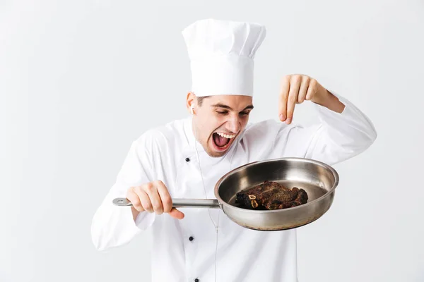 愉快的厨师厨师穿着制服显示煎锅与熟牛排隔离在白色背景 调味料 — 图库照片