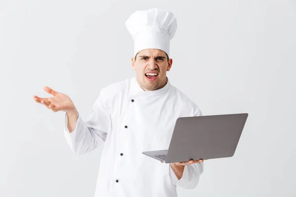 Cozinheiro Chef Confuso Vestindo Uniforme Sobre Fundo Branco Segurando Computador — Fotografia de Stock
