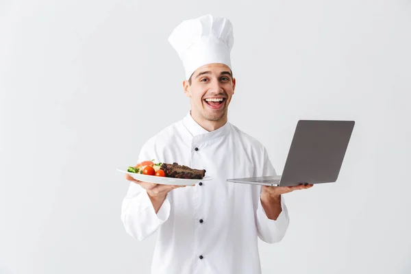 Cocinero Emocionado Vistiendo Uniforme Pie Sobre Fondo Blanco Sosteniendo Ordenador — Foto de Stock