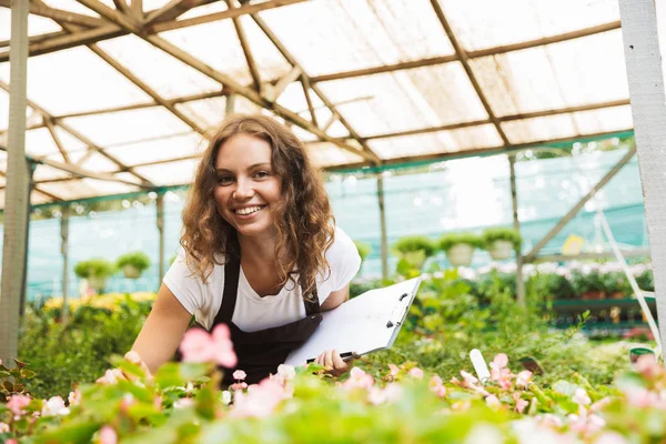 タブレットでノートを書いて 温室で働いて幸せな若い女 — ストック写真