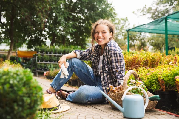 水で魅力的な美しい女庭師が温室の花近くの作業 — ストック写真