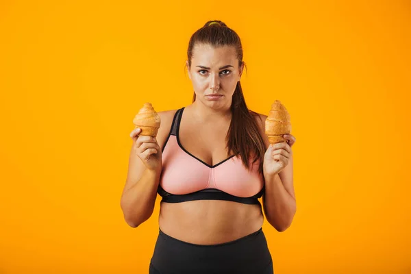 Image Upset Chubby Woman Tracksuit Holding Two Croissants Both Hands — Stock Photo, Image