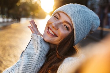 Güzel ve genç birbayan sonbahar ceket ve açık havada yürüyüş, bir selfie alarak bir şapka giymiş
