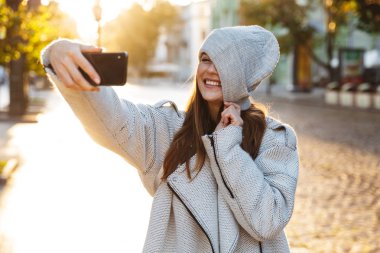 Güzel ve genç birbayan sonbahar ceket ve açık havada yürüyüş, bir selfie alarak bir şapka giymiş