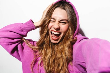 Beyaz arka plan üzerinde izole selfie fotoğraf çekerken mutlu kadın 20'li yaşlarda sweatshirt giyen gülen portre