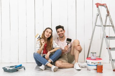 Fotoğraf güzel çift erkek ve yenileme kapalı yaparken katta merdiven yakınındaki beyaz duvar üzerinde oturan kadın