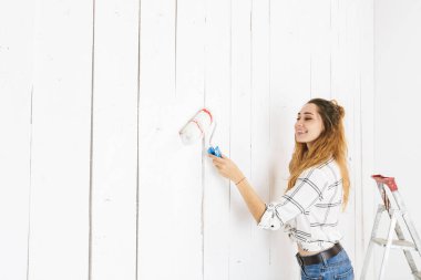 Görüntü kadın 20'li yaşlarda resim beyaz duvar eğlenceli ve boya silindiri kullanarak yenileme yapma