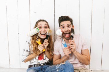 Görüntü heyecanlı çift erkek ve kadın boya merdaneleri tutan ve 