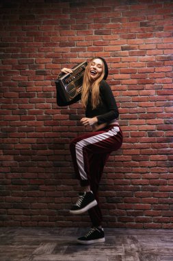Tam boy görüntü beyaz kadının 20'li yaşlarda duvara karşı duran ve boombox holding