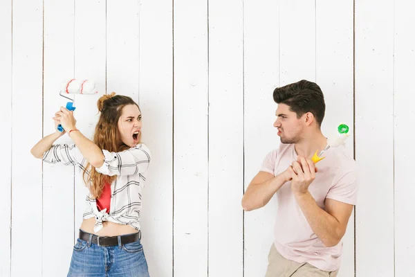 面白いカップル男性と女性の絵の白い壁のペイント ローラーを使用して革新を作るイメージ — ストック写真