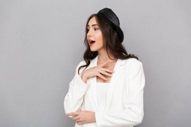 Uzak seyir gri arka plan üzerinde izole bere ayakta giyen bir heyecanlı genç kadın portresi