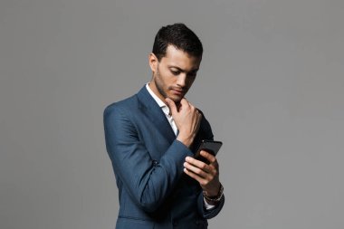 Görüntü gri duvar arka plan cep telefonuyla izole bir yakışıklı genç iş adamı.