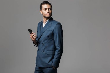 Görüntü gri duvar arka plan cep telefonuyla izole bir yakışıklı genç iş adamı.