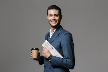 Görüntü gri arka plan üzerinde izole gazete ve paket servisi olan restoran kahve holding resmi elbiseli çekici Arapça işadamı 30'lu