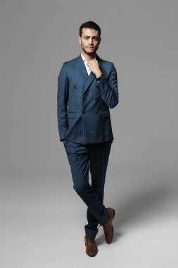 Tam boy görüntü yakışıklı Arapça işadamı 30'lu resmi kıyafetli ayakta ve gri arka plan üzerinde izole kamera bakıyor