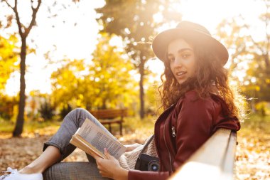 Kitap okuma parkta bir bankta oturmuş güzel şirin bir kadın görüntüsü.