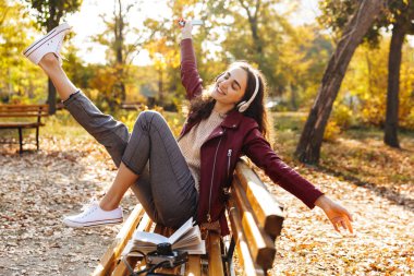 Kulaklık ile müzik dinlemek parkta bir bankta oturan neşeli genç kız