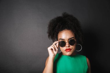 Güzel bir afro Amerikalı kadın siyah arka plan üzerinde izole ayakta, poz güneş gözlüğü takıyor portresi