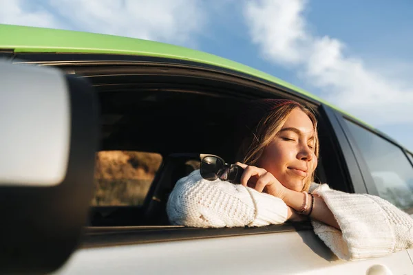 日没時に車を運転して 窓を見て笑みを浮かべて少女 — ストック写真