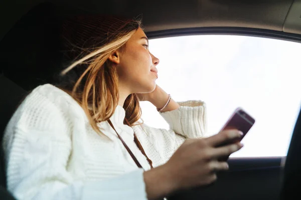 Beautiful Young Woman Holding Mobile Phone While Sitting Car Looking — Stock Photo, Image