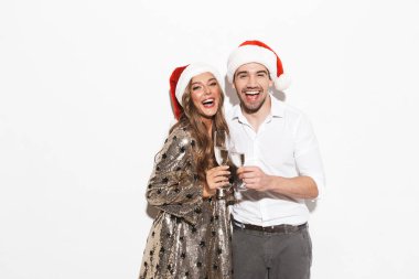 Neşeli genç akıllıca köpüklü şampanya içmek beyaz arka plan üzerinde izole çift kutluyor yeni yıl partisi giyinmiş