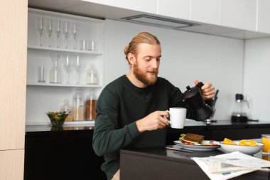 Mutfakta otururken gazete okuma Kahvaltı, yakışıklı genç adam