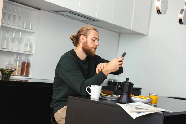 Bonito Jovem Tomando Café Manhã Lendo Jornal Enquanto Sentado Cozinha — Fotografia de Stock