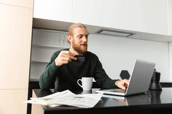 Joven Ocupado Trabajando Computadora Portátil Casa Sentado Cocina Bebiendo — Foto de Stock