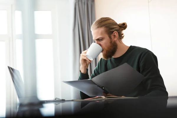 Joven Ocupado Trabajando Computadora Portátil Casa Sentado Cocina Bebiendo — Foto de Stock