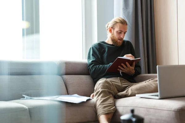 Knappe Jongeman Thuiswerken Zittend Een Bank Met Behulp Van Laptopcomputer — Stockfoto