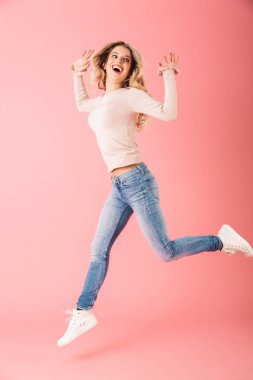 Kazak atlama üzerinde pembe arka plan izole giymiş mutlu bir genç kadın portresi tam uzunlukta