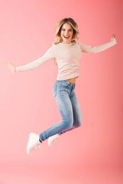 ピンクの背景に分離されたセーター ジャンプを身に着けている幸せな若い女の完全な長さの肖像画 — ストック写真