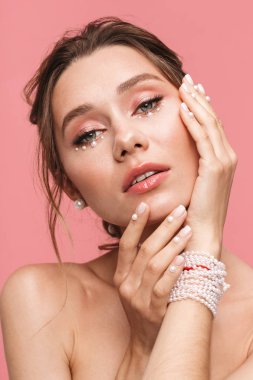 Güzellik Portresi beyaz inci giymiş pembe arka plan üzerinde izole çekici bir genç üstsüz kadın poz