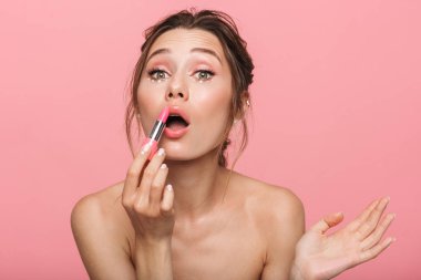 Genç ve güzel bir kadının poz görüntü ruj makyaj tutarak pembe duvar arka plan üzerinde izole.