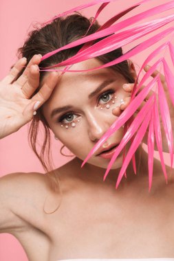 Çekici bir genç üstsüz kadın pembe hurma ile poz güzellik portresi beyaz inci giymiş pembe arka plan üzerinde izole bırakır