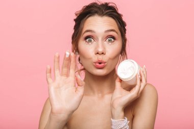 Şok oldukça genç bir kadının poz görüntü pembe duvar arka plan üzerinde izole kendine iyi bak onu deri krem.