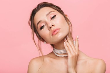 Güzellik Portresi beyaz inci kolyesi, pembe arka plan üzerinde izole çekici bir genç üstsüz kadın poz