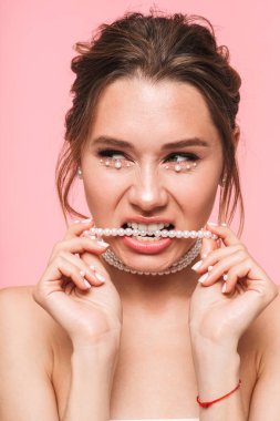 Güzellik Portresi beyaz inci giymiş pembe arka plan üzerinde izole çekici bir genç üstsüz kadın poz