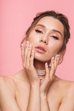 Güzellik Portresi beyaz inci kolyesi, pembe arka plan üzerinde izole çekici bir genç üstsüz kadın poz