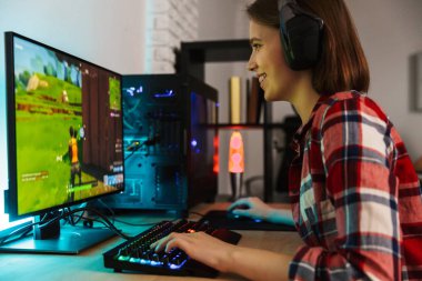 Heyecanlı kız oyun oturma masada bir bilgisayarda kapalı online oyun oynamak